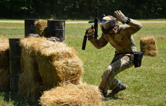 joven con las manos levantadas mientras juega al paintball.jpg
